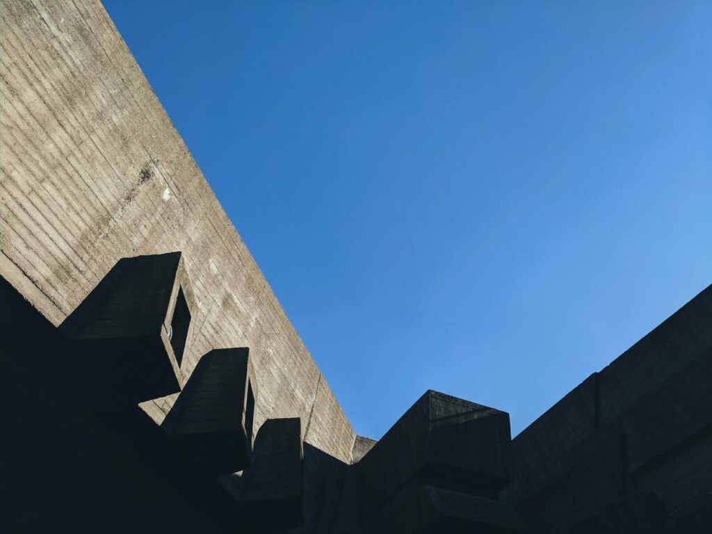 low-angle photography of gray concrete building under calm blue sky