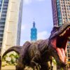 dinosaur with open mouth beside buildings still selective focus photography of