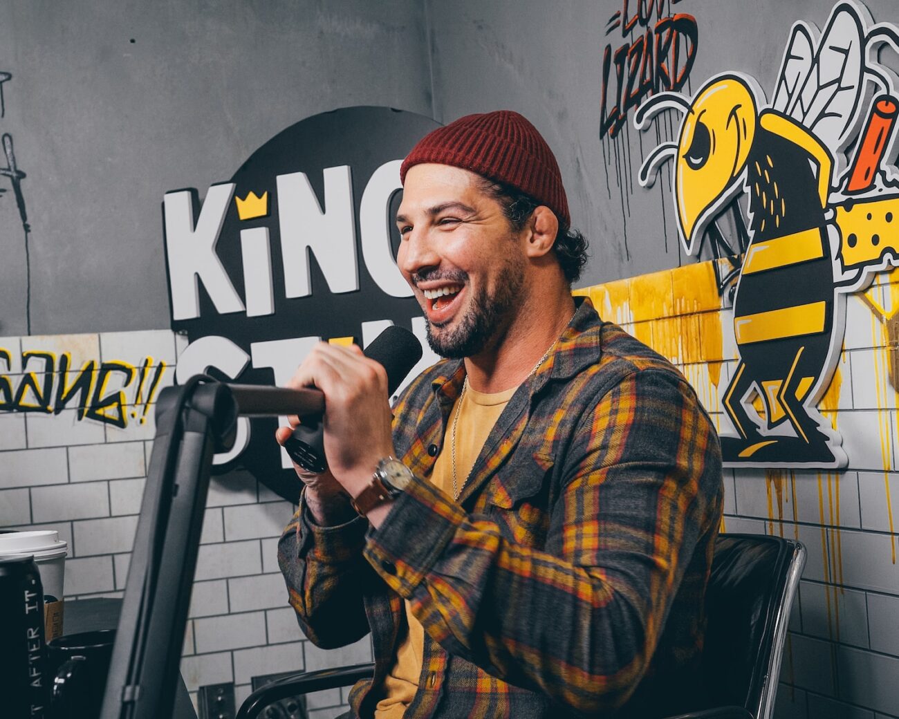 man in red knit cap and yellow and black plaid dress shirt holding microphone