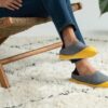 person in blue denim jeans and yellow slip on shoes sitting on brown wooden chair on on on on on