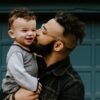 man carrying baby boy and kissing on cheek