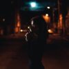 woman in black leather jacket standing on street during night time