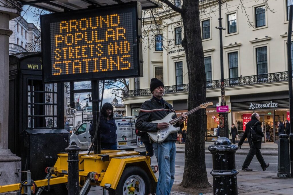 man playing guitar near LED signage