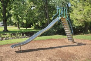 a slide in a park with trees in the background