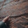 a person pointing at a rock with writing on it
