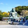 a large buddha statue sitting in the middle of a park