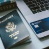 a passport sitting next to a laptop on a desk