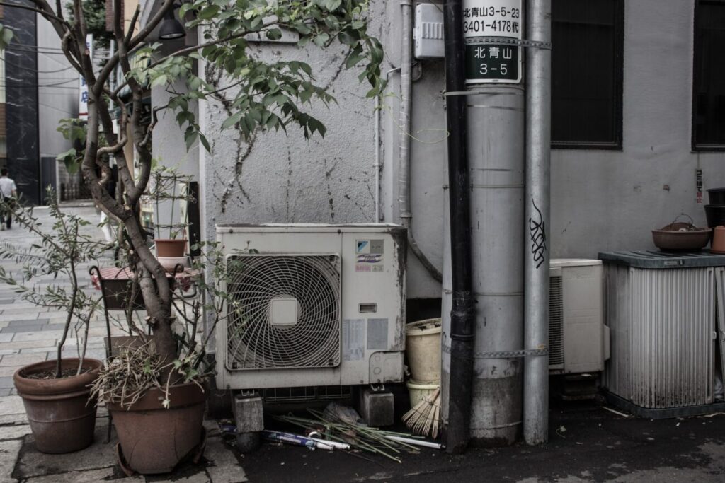 air condenser beside two potted plants outside building