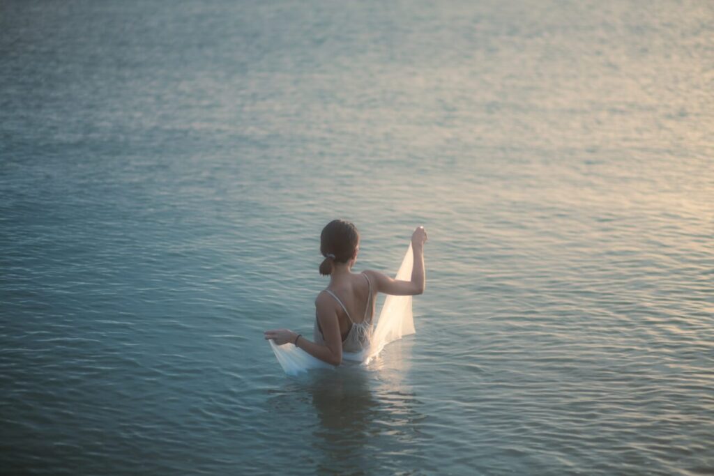 a woman sitting on a surfboard in a body of water