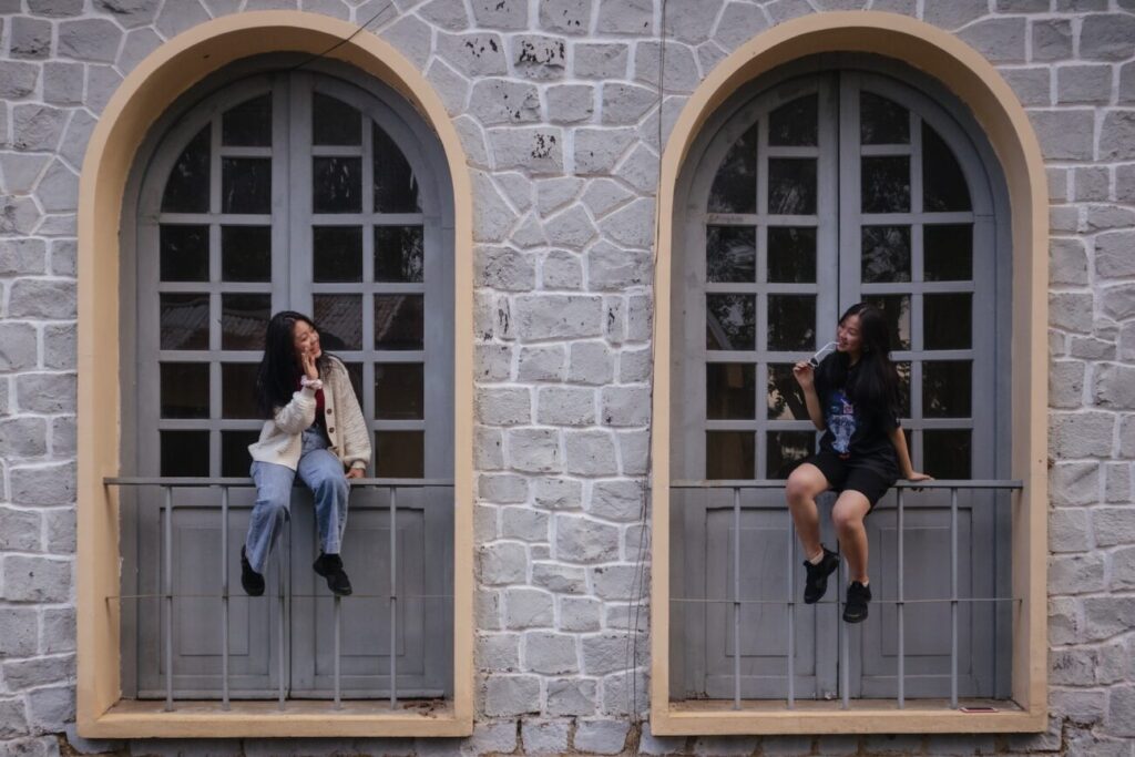 2 women sitting on window