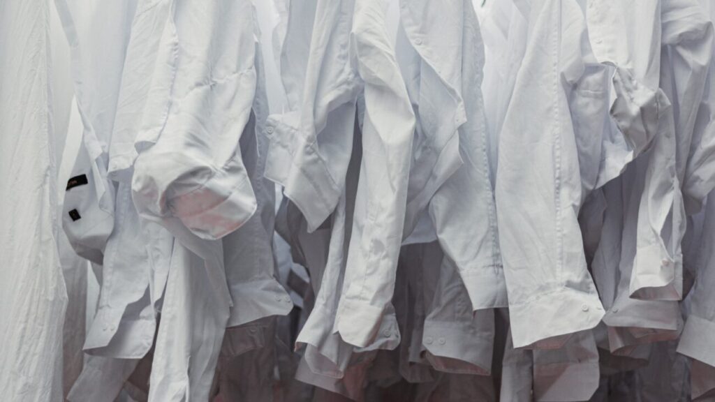 a bunch of white shirts hanging on a rack