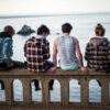 four person sitting on bench in front of body of water