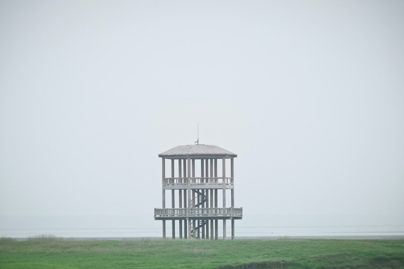 white wooden tower on green grass field under white sky during daytime