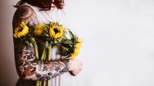 woman holding yellow sunflowers on her right arm
