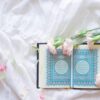 blue and white book on white and pink floral textile
