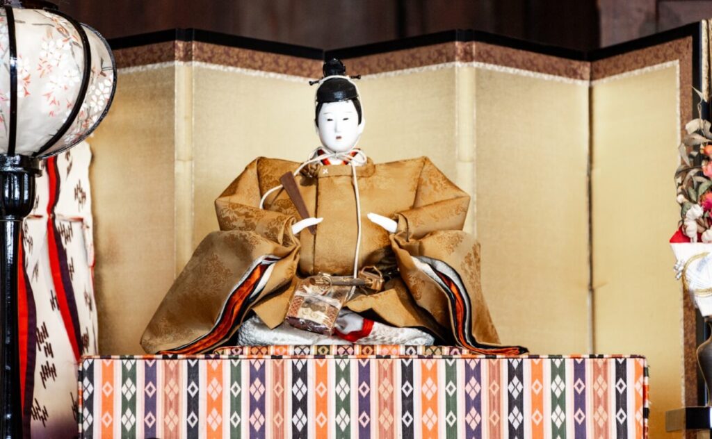 a geisha doll sitting on a table next to a lamp