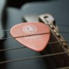 selective focus photography of brown guitar pick on guitar strings