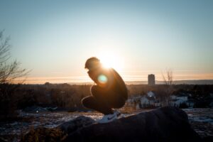 man in black jacket sitting on rock during daytime