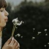 woman blowing dandelions